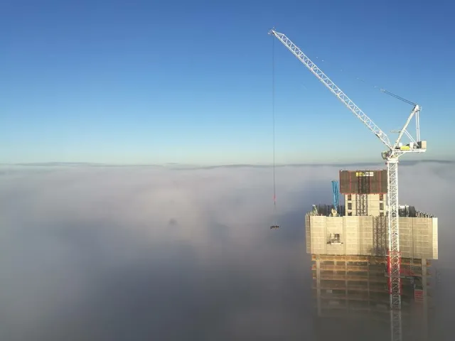 Bouw van de Owen Street woontoren in Manchester met bouwkraan boven de wolken