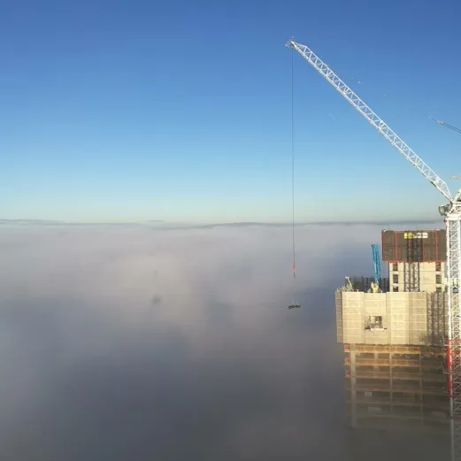 Bouw van de Owen Street woontoren in Manchester met bouwkraan boven de wolken