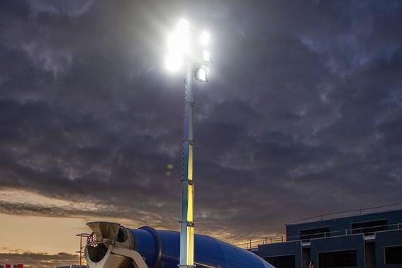 Mobiele lichtmast verlicht een bouwplaats met betonwagen tijdens avondwerk