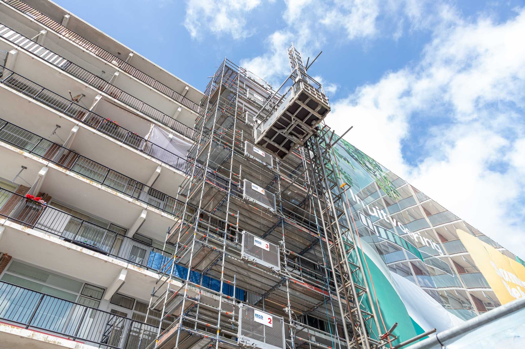 Bouwlift gemonteerd in steiger bij flatgebouw voor personen- en goederenvervoer